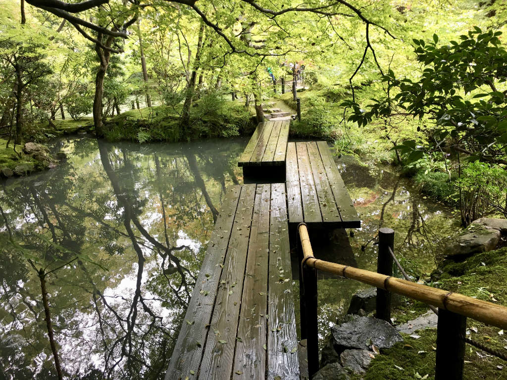 Pont en bois traversant un ruisseau, dans un jardin au Japon